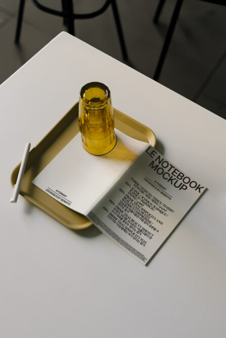 Notebook with blue cover inside cream tray with amber glass bottle on top