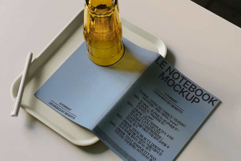 Notebook with blue cover in white tray with amber glass bottle above it