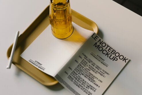 Notebook mockup with yellow glass and tray on white surface suitable for designers. Ideal for showcasing layouts templates product design or branding.