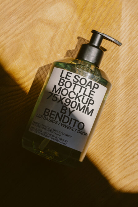Golden liquid soap bottle with black pump dispenser on wooden surface
