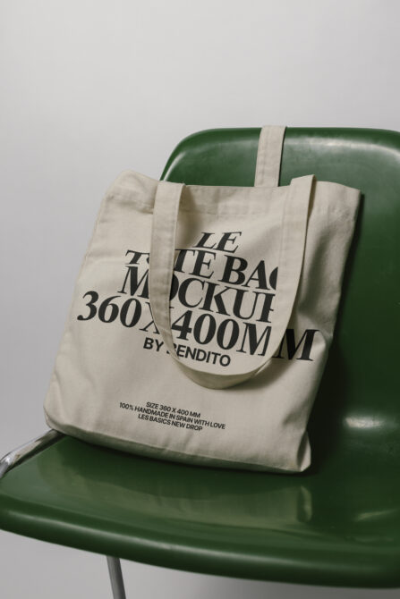 Natural linen tote bag with overlapping serif text mockup on green chair