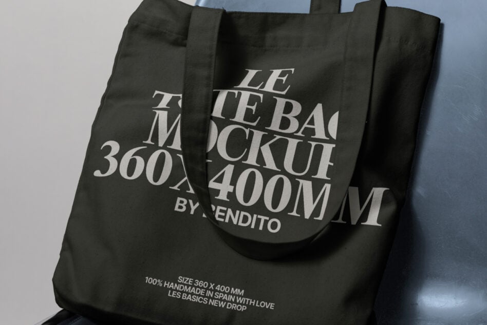 Black tote bag mockup with large typography draped over modern chair