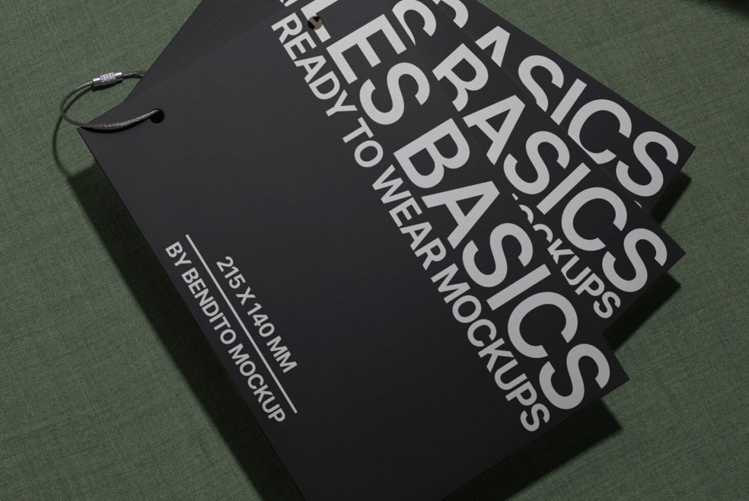 Mockup presentation of black hangtags labeled Basics Ready to Wear 215x140 mm on green fabric background ideal for fashion designers and branding.