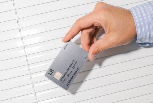 Hand holding gray credit card mockup over lined paper background