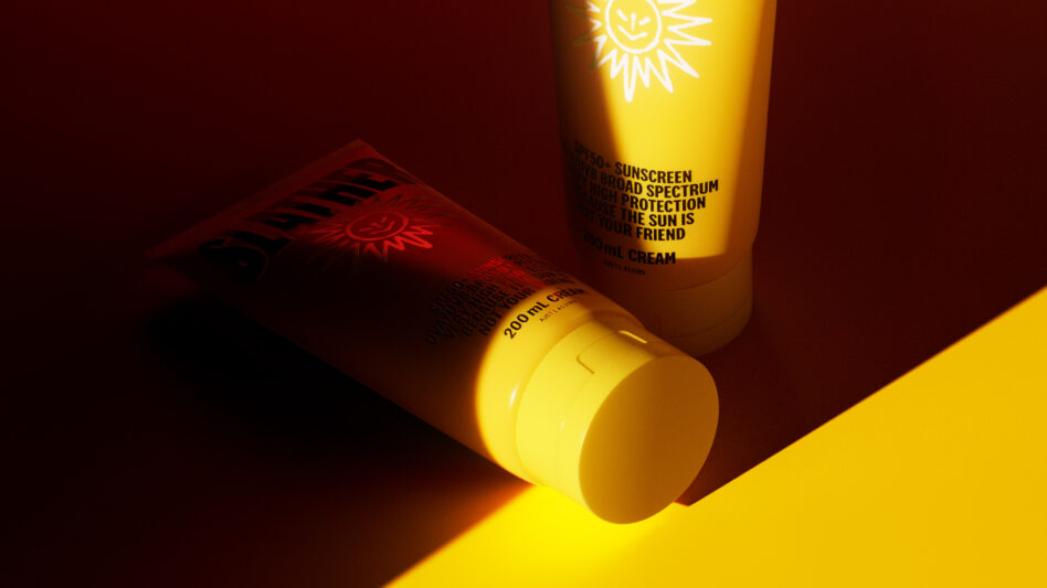 Sunscreen tube lying down with smiley sun logo on dark red backdrop