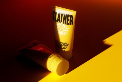 Tube of sunscreen labeled SLATHER on vibrant red and yellow background with dramatic lighting mockup perfect for showcasing skincare product designs.