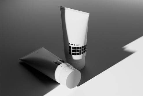 Minimalist mockup of two cosmetic tubes with monochrome grid design in dramatic lighting. Perfect for showcasing branding or graphic design projects.