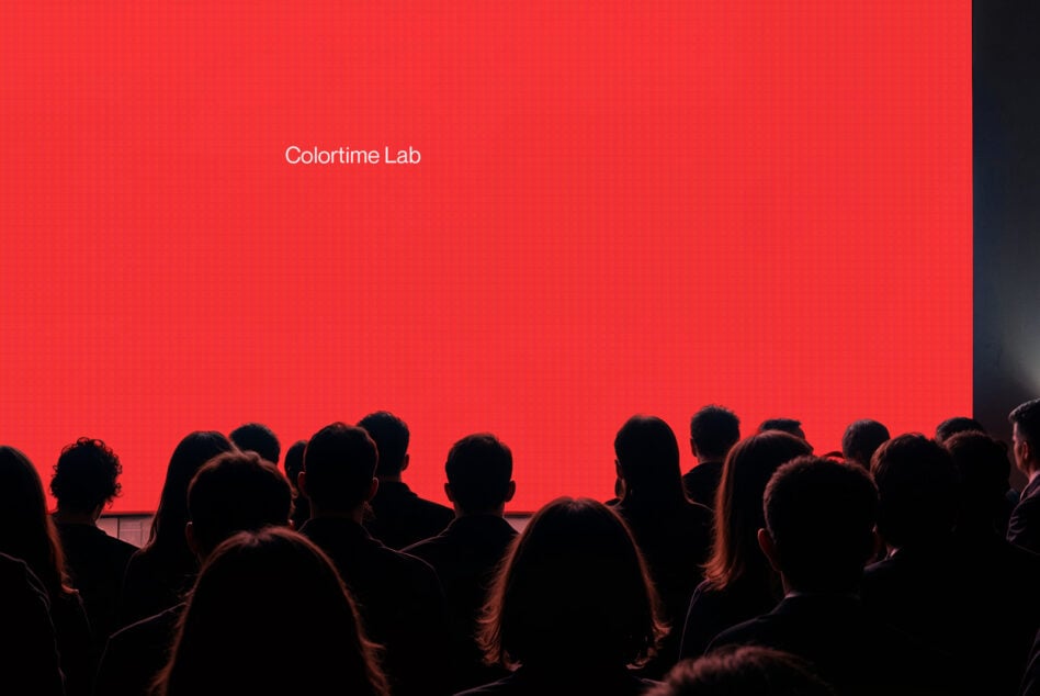 Bright red screen display with Colortime Lab text viewed by audience crowd