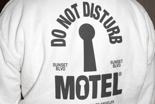 Back of white robe featuring bold graphic text do not disturb motel with keyhole design and Sunset Blvd. Perfect for graphics or typography inspiration.