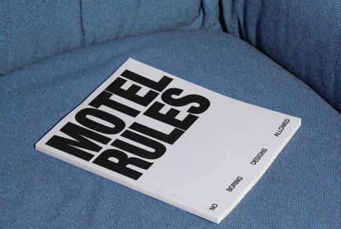 Magazine with bold text Motel Rules on a blue fabric background. Ideal for graphic designers seeking layout inspiration or typography mockups.