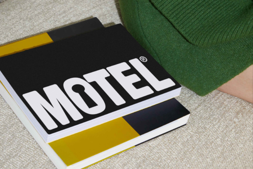 Typography book with bold MOTEL title on black cover lying on sofa. Perfect for designers. Keywords: graphics, mockups, fonts, templates, design asset.