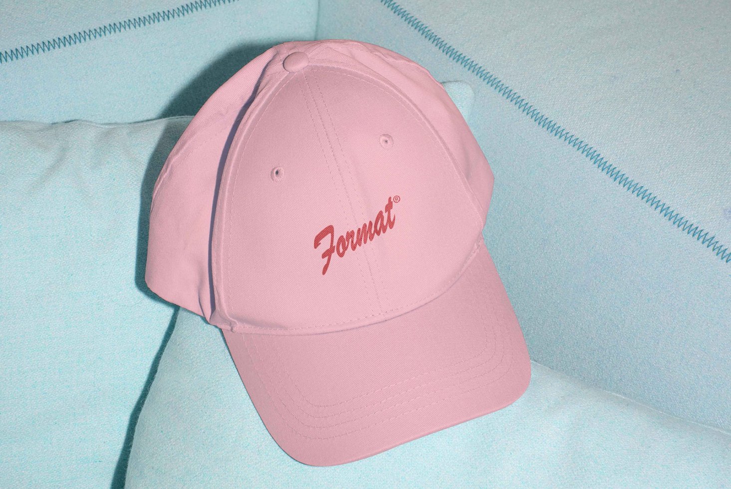 Pink cap mockup on blue fabric background. Ideal for fashion designers graphic templates branding presentations. High resolution digital asset.