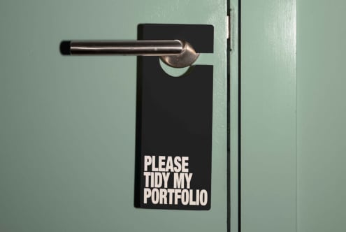 Door hanger mockup saying Please Tidy My Portfolio on a door handle. Dark design on a teal background. Perfect for graphic design projects and templates.