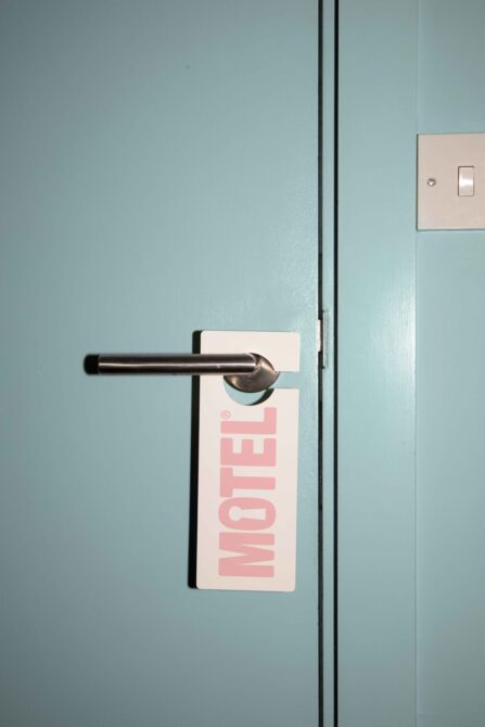 Pink door hanger mockup hanging from metal handle on soft blue wall