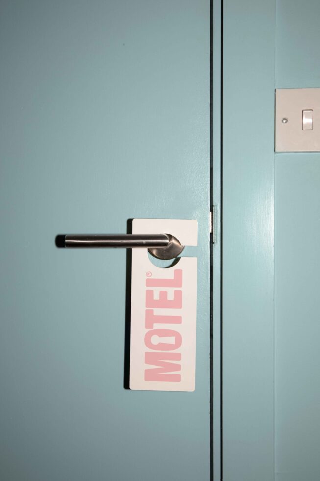 Mockup of a turquoise door with metallic handle and a motel sign. Ideal for hotel branding designs and hospitality templates. High-quality asset for designers.