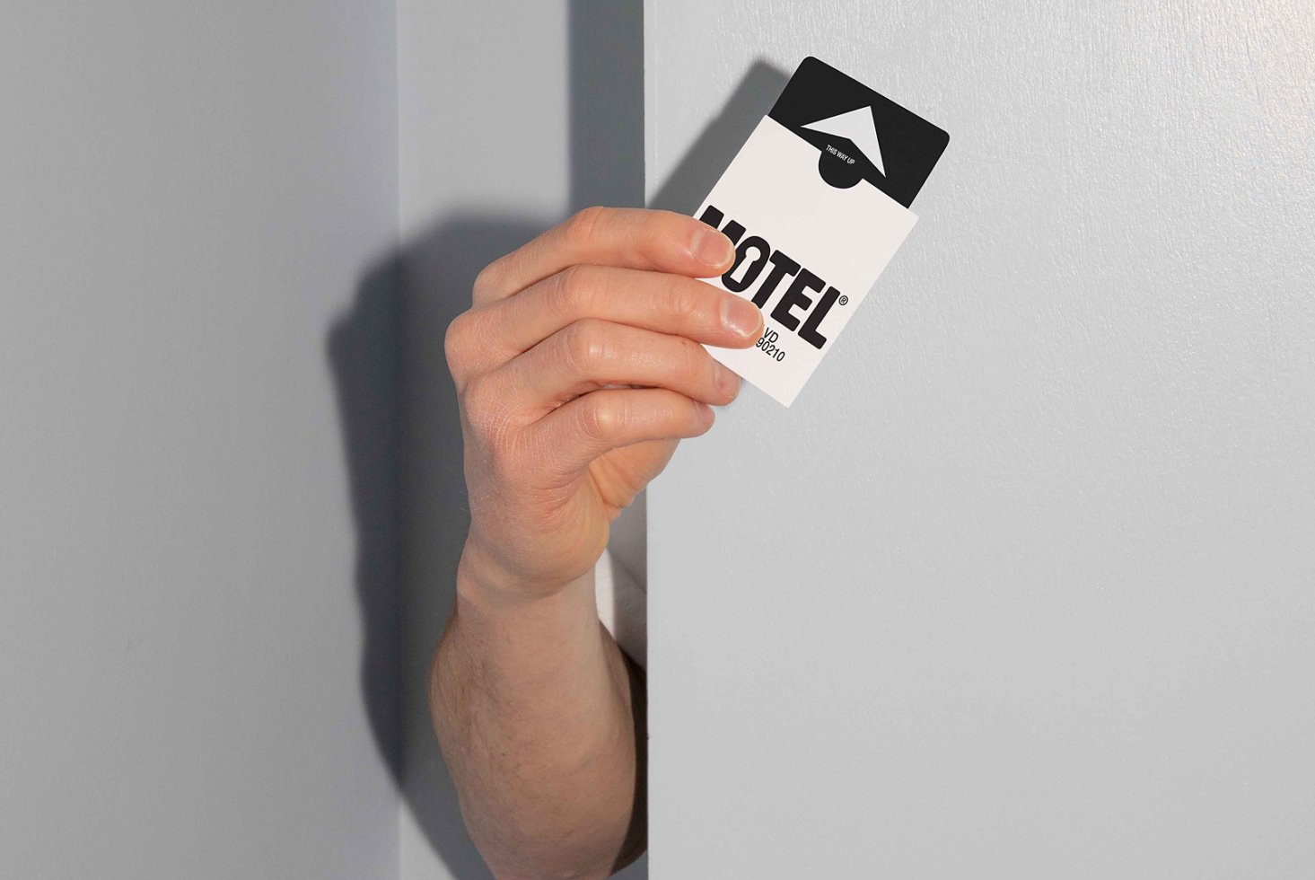Hand holding hotel key card with modern typography design in minimalist setting ideal for branding mockups templates for graphic designers