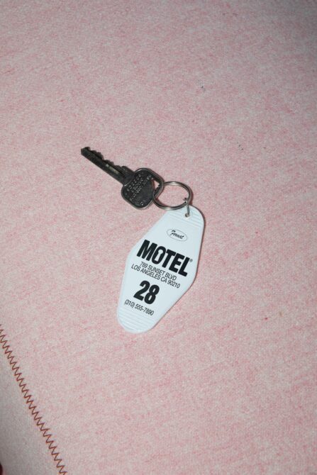 Vintage motel keychain on pink fabric background with room number for mockup designs travel graphics retro aesthetic and templates.