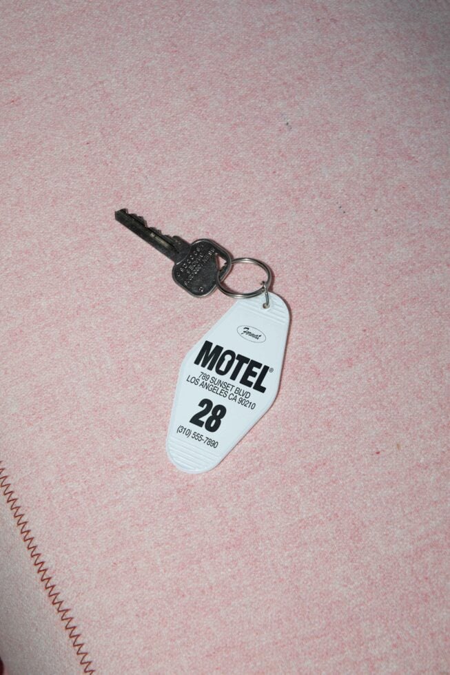 Vintage motel keychain on pink fabric background with room number for mockup designs travel graphics retro aesthetic and templates.