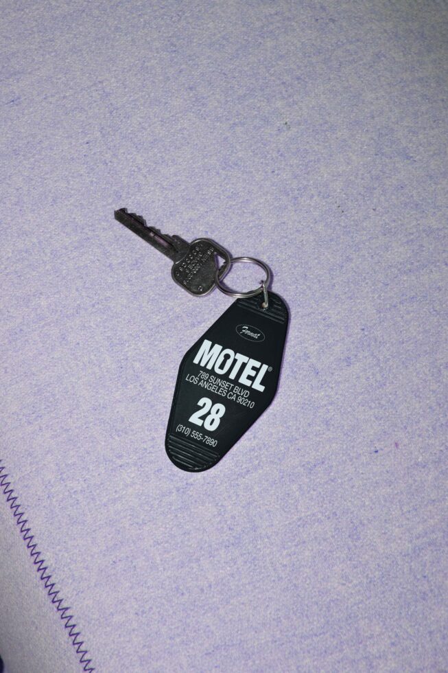 Motel key with a vintage keyring tag labeled 28 resting on a textured surface ideal for graphic design templates nostalgia aesthetic SEO keywords