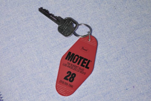 Red vintage motel key tag with key resting on a textured blue background ideal for use in mockups and design templates for print or digital media.