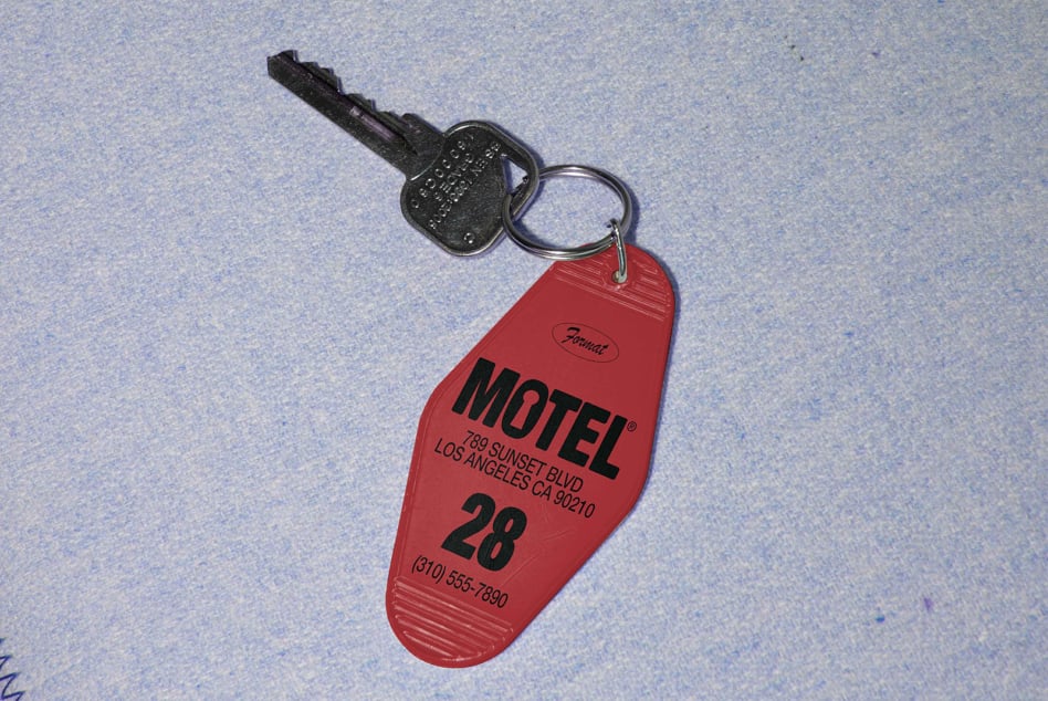 Red vintage motel key tag with key resting on a textured blue background ideal for use in mockups and design templates for print or digital media.