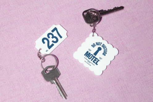 Keychains with retro motel tags on a pink textured background, ideal for vintage design mockups or graphic templates for designers and creatives.