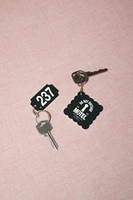 Vintage motel key tags with room number 287 plus do not disturb charm on pink background