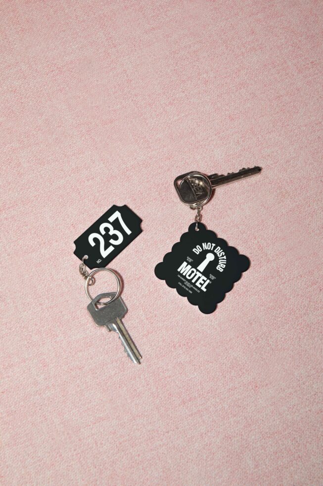 Vintage motel key tags with room number 287 plus do not disturb charm on pink background