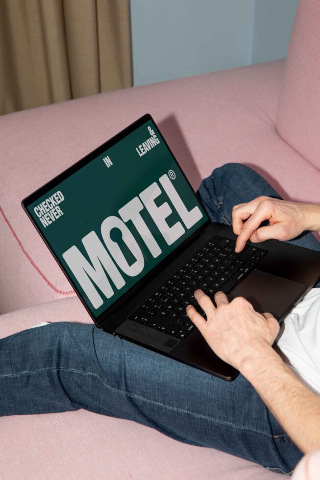Person using laptop displaying graphic design with the word Motel bold on sofa digital assets mockup template creative workspace designer tool