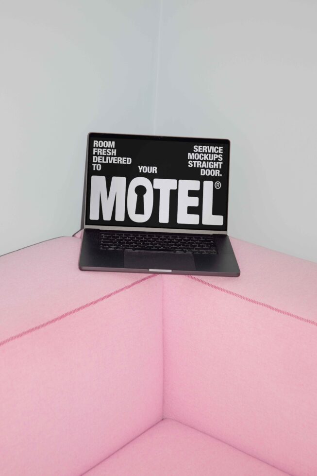 Laptop displaying typography mockup on black screen perched on pink couch corner minimalist design mockups digital assets for designers SEO keyword marketplace