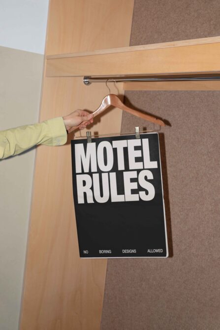 Motel Rules sign on black background hanging from wooden hanger in closet