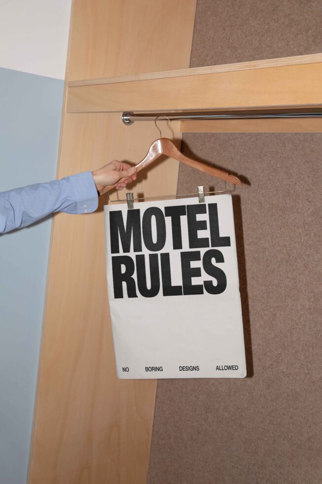 Hand holding hanger with poster reading Motel Rules inside closet minimalist design art perfect for templates mockups graphic designers trendy style