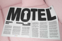 Motel magazine on pink couch with bold typography spread across pages