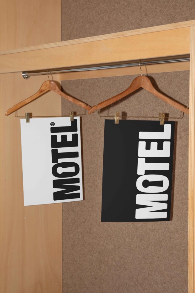 Vintage motel-themed typography posters hanging on wooden clothes hangers. Black and white graphics ideal for designers. Modern retro poster design.