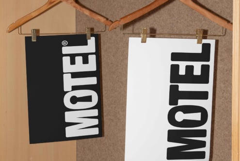 Poster mockup featuring black and white MOTEL designs on clip hangers against a wooden background perfect for designers and branding presentations.