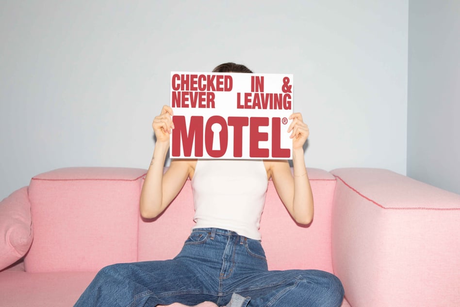 Person holding red motel sign on pastel pink couch mockup