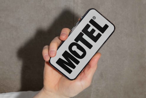 Hand holding phone with bold MOTEL text design. Ideal for templates mockups branding. Minimalist style photo. Perfect for graphic designers.