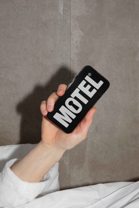 Hand holding phone displaying bold Motel font against neutral background. Ideal for designers seeking typography inspiration. Graphic, fonts, digital asset.