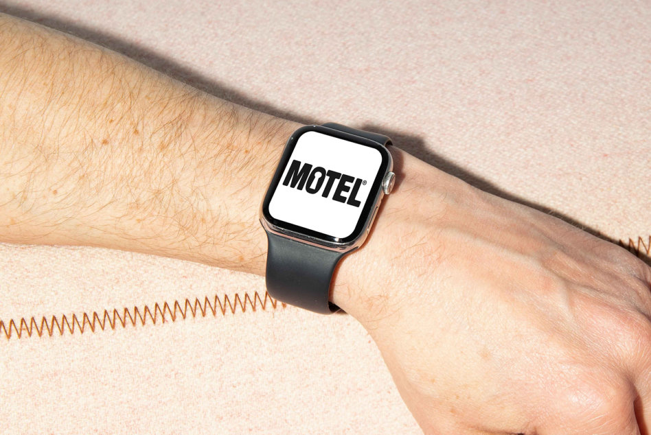 Smartwatch on wrist displaying motel text on white watch face