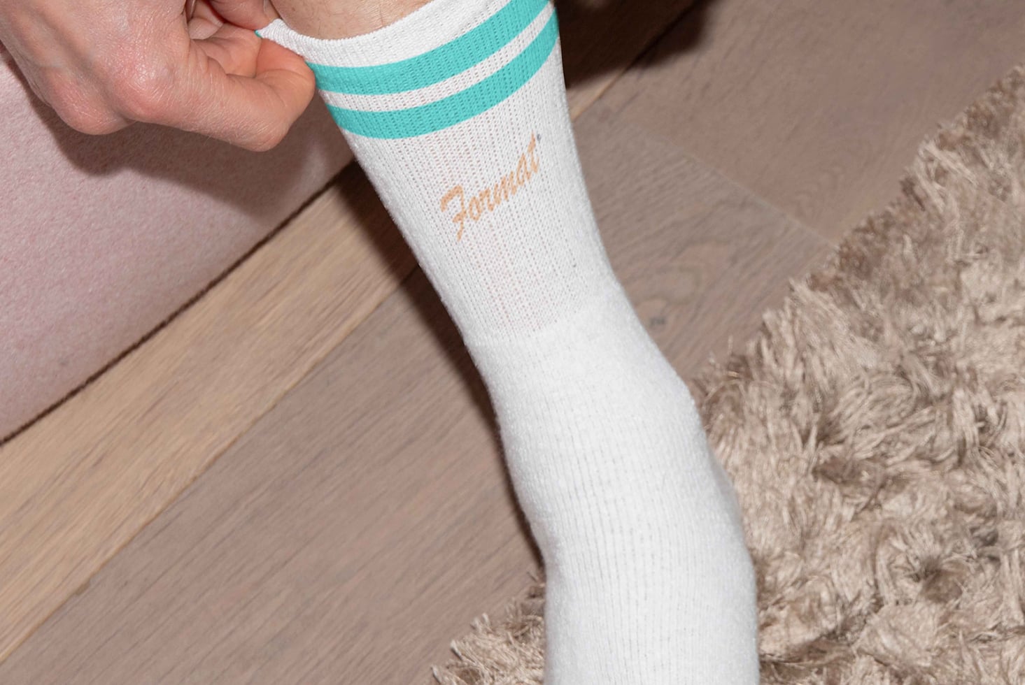 Close-up of a person wearing a white sock with teal stripes and the word Format on it. Perfect for mockup designs showcasing custom sock graphics.