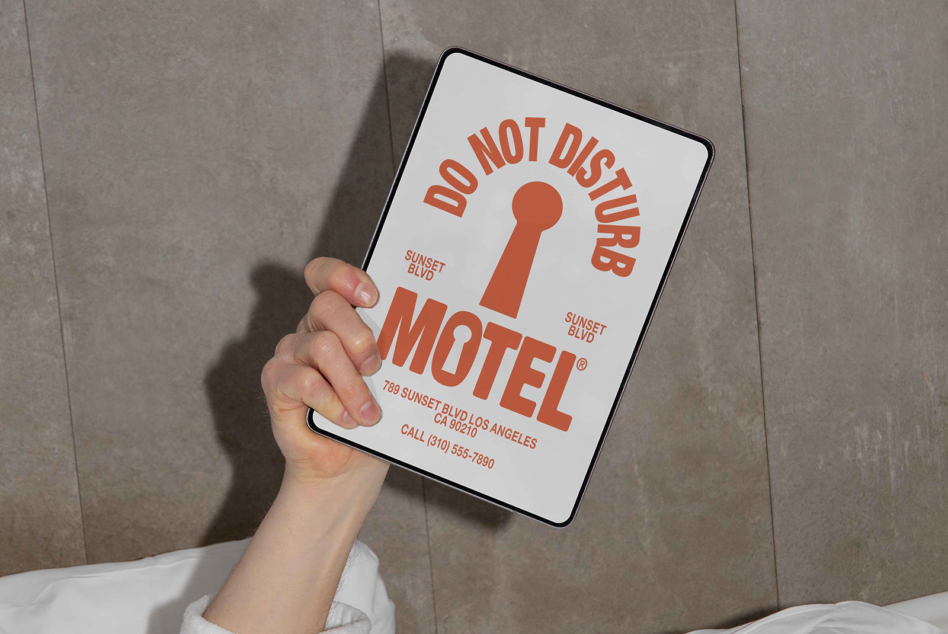 Hand holding tablet mockup displaying red do not disturb motel sign