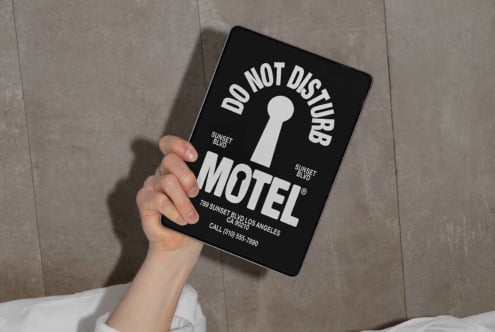 Hand holding digital tablet with motel-themed do not disturb sign mockup. Ideal for showcasing graphic design templates and typography assets for designers.