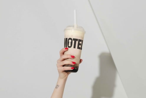 Hand holding bubble tea cup with bold font design against a white background. Perfect for mockups or branding templates for graphic designers.