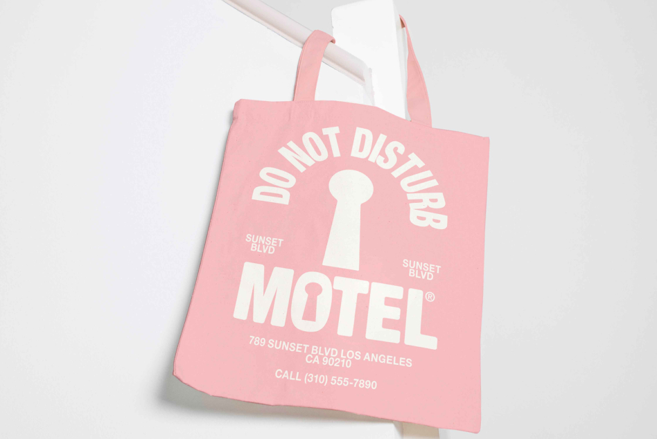 Soft pink tote bag featuring Do Not Disturb Motel keyhole graphic in cream white