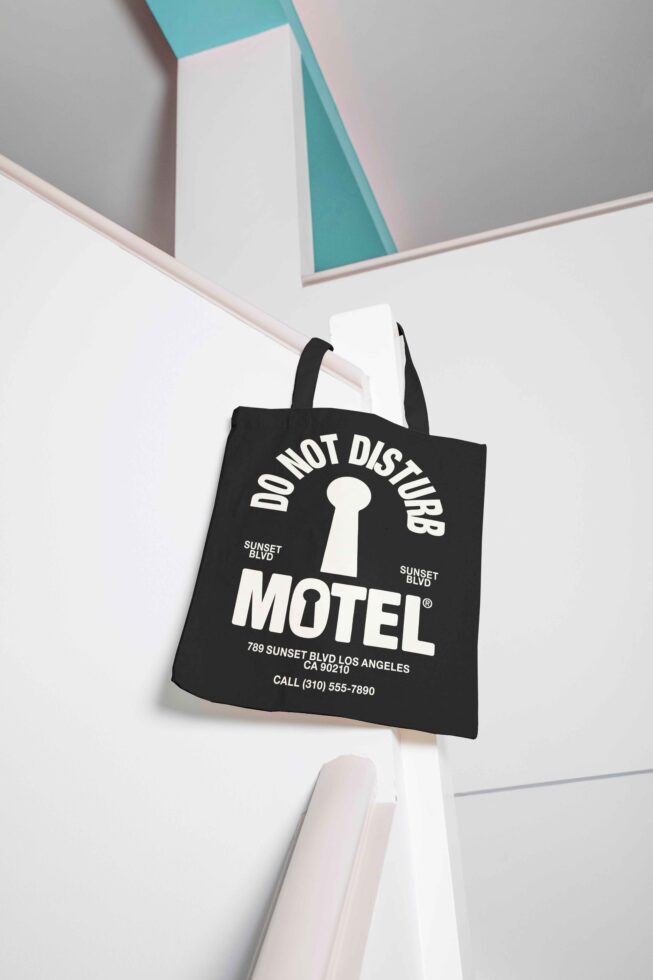 Tote bag mockup on modern stairs; features bold Do Not Disturb Motel text and keyhole graphic; ideal for branding, advertising, and graphic design projects.