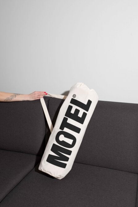 White cylindrical pillow mockup with black text leaning on dark couch