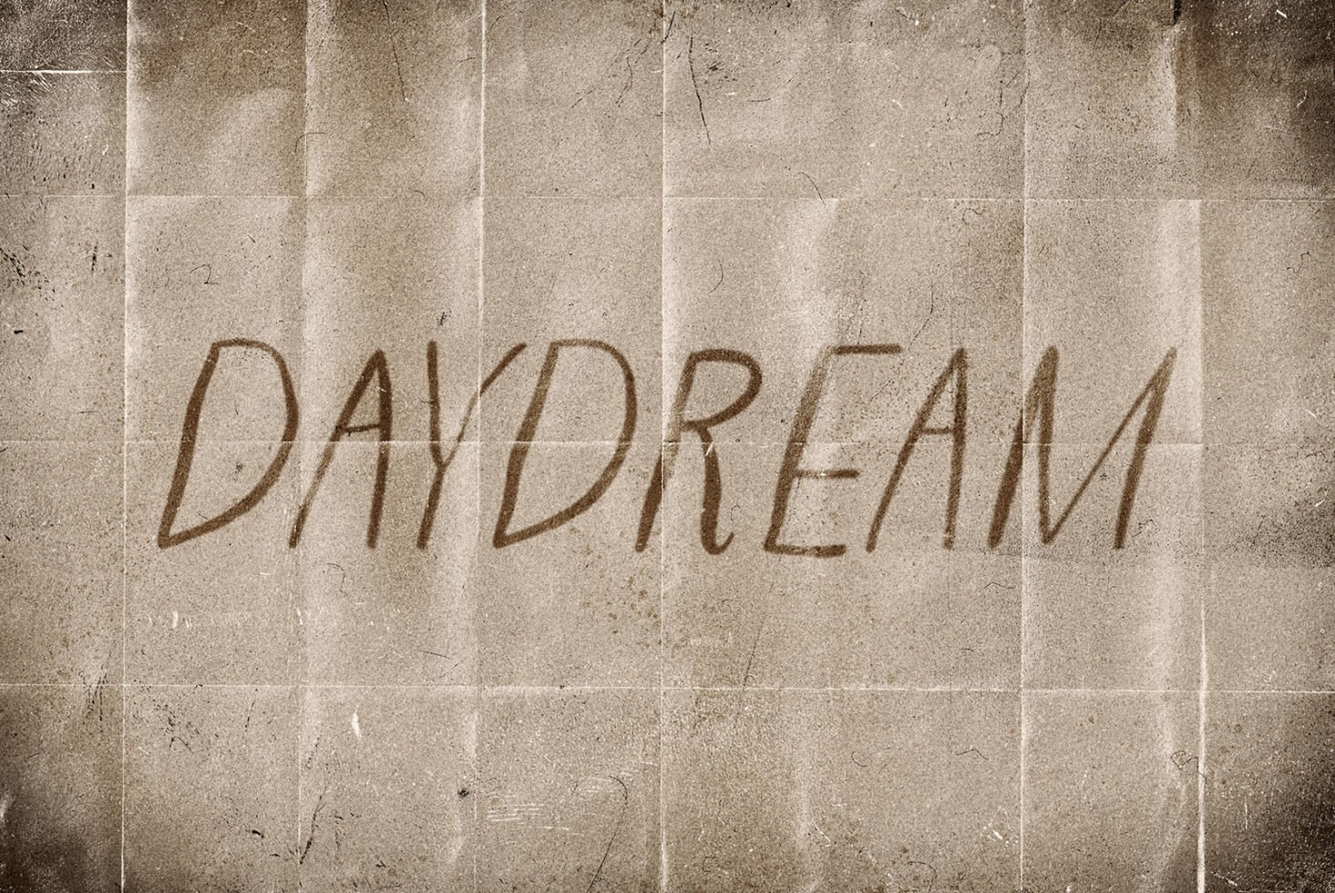 Vintage paper texture with hand-drawn text Daydream in a handwritten style ideal for graphic design templates posters and typography projects.