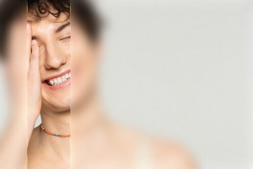 Smiling person with hand on face wearing colorful necklace partially blurred background portrait photography design asset digital graphics.