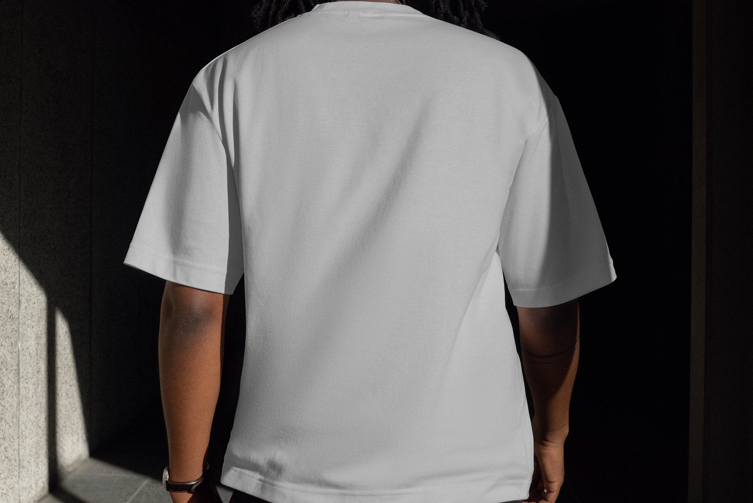 Back view of person wearing plain white T-shirt mockup in natural lighting. Perfect for clothing design presentations and fashion templates.