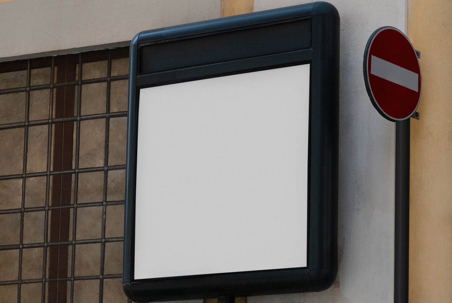 Blank tablet screen in black frame mounted on textured wall next to traffic sign